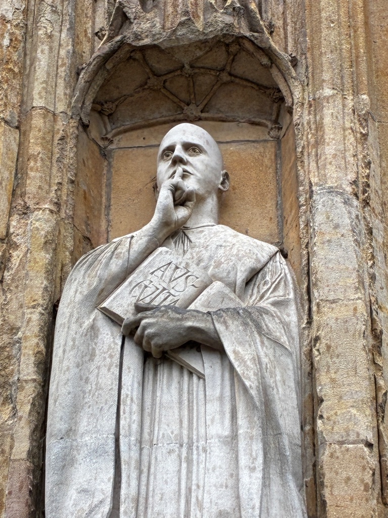 Stone cathedral statue with finger to lips, gesturing silence